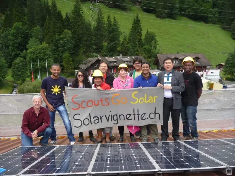 Scouts holding a banner next to a solar panel